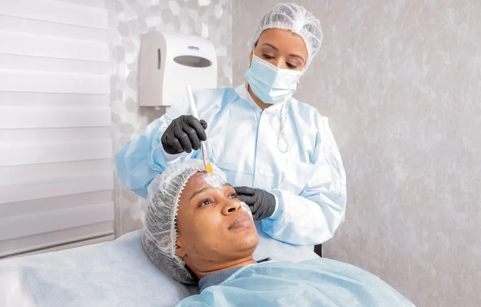A beautician applies a treatment to a woman's face in a spa, focusing on skincare.
