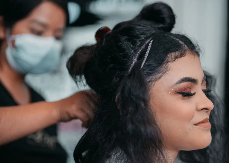 Close-up of professional hair styling at a salon with a focus on makeup artistry.