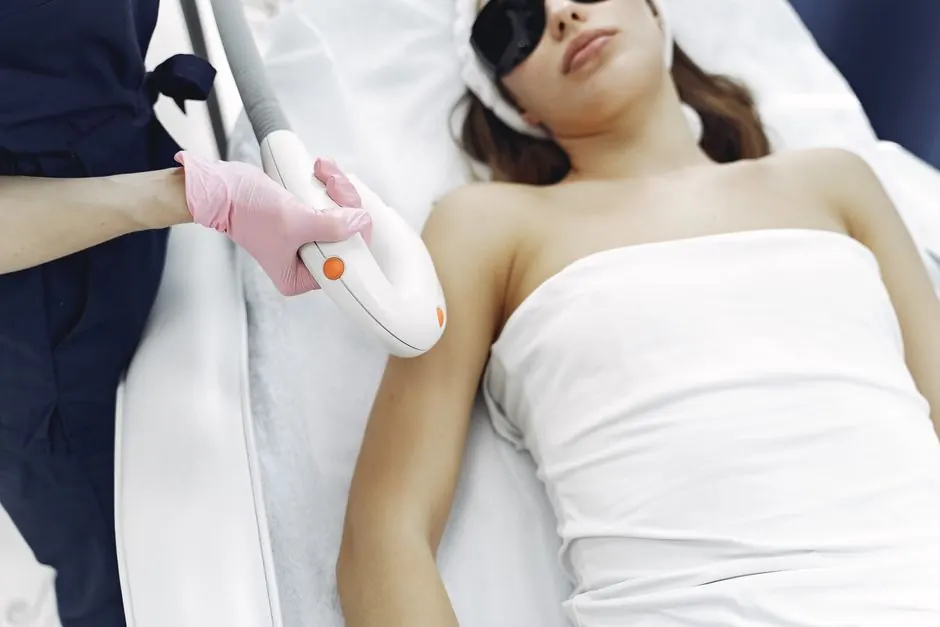 From above of unrecognizable cosmetologist in uniform and latex gloves using modern equipment for cosmetic services in contemporary salon